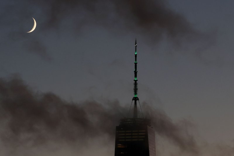 Clouds pass by a waxing crescent moon that sets behind One World Trade Center in September 2023 in New York City. The crescent moon will be the centerpiece of April's final astronomical event as it bunches up with Venus, Saturn and Mercury in the eastern sky on Friday morning. File Photo by John Angelillo/UPI